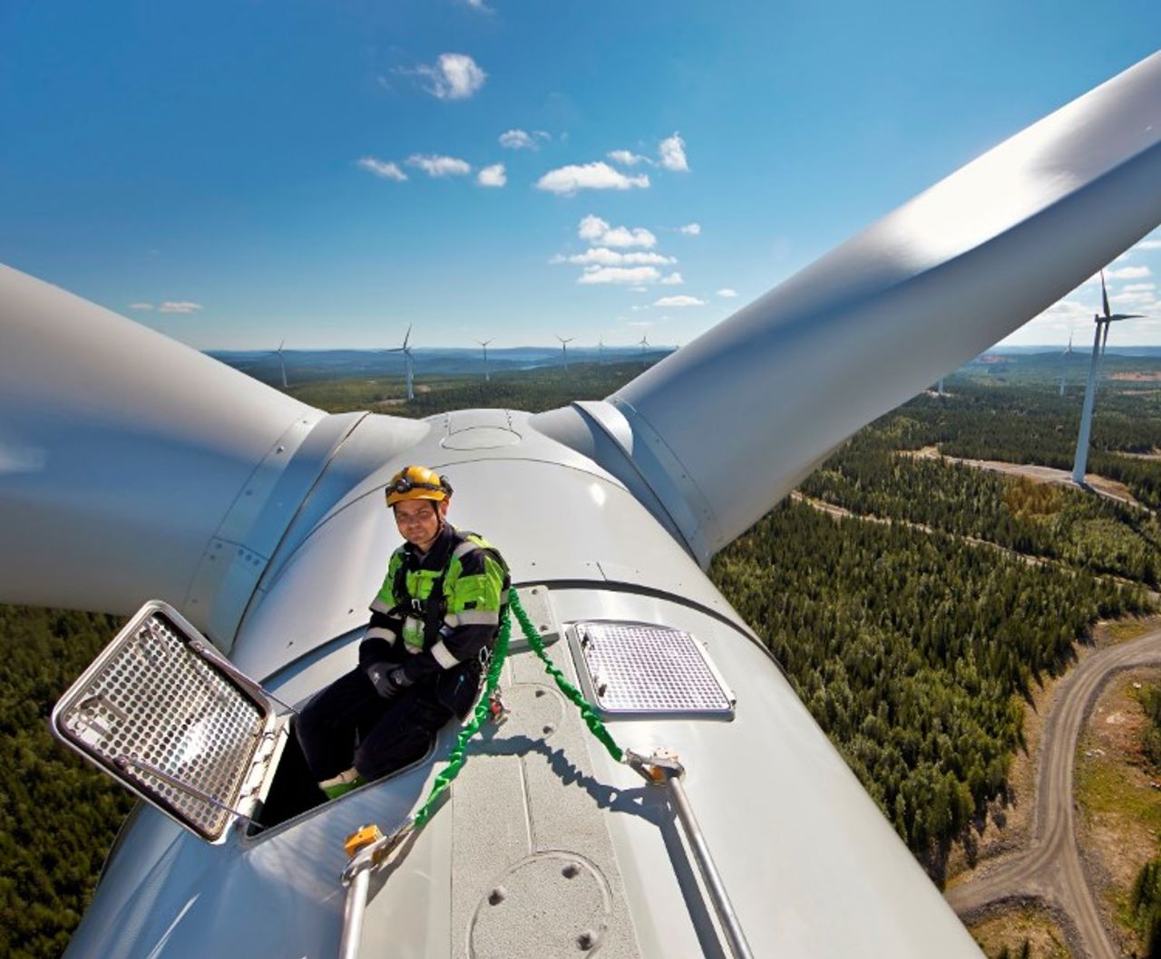 Mann auf der Spitze einer Windkraftanlage