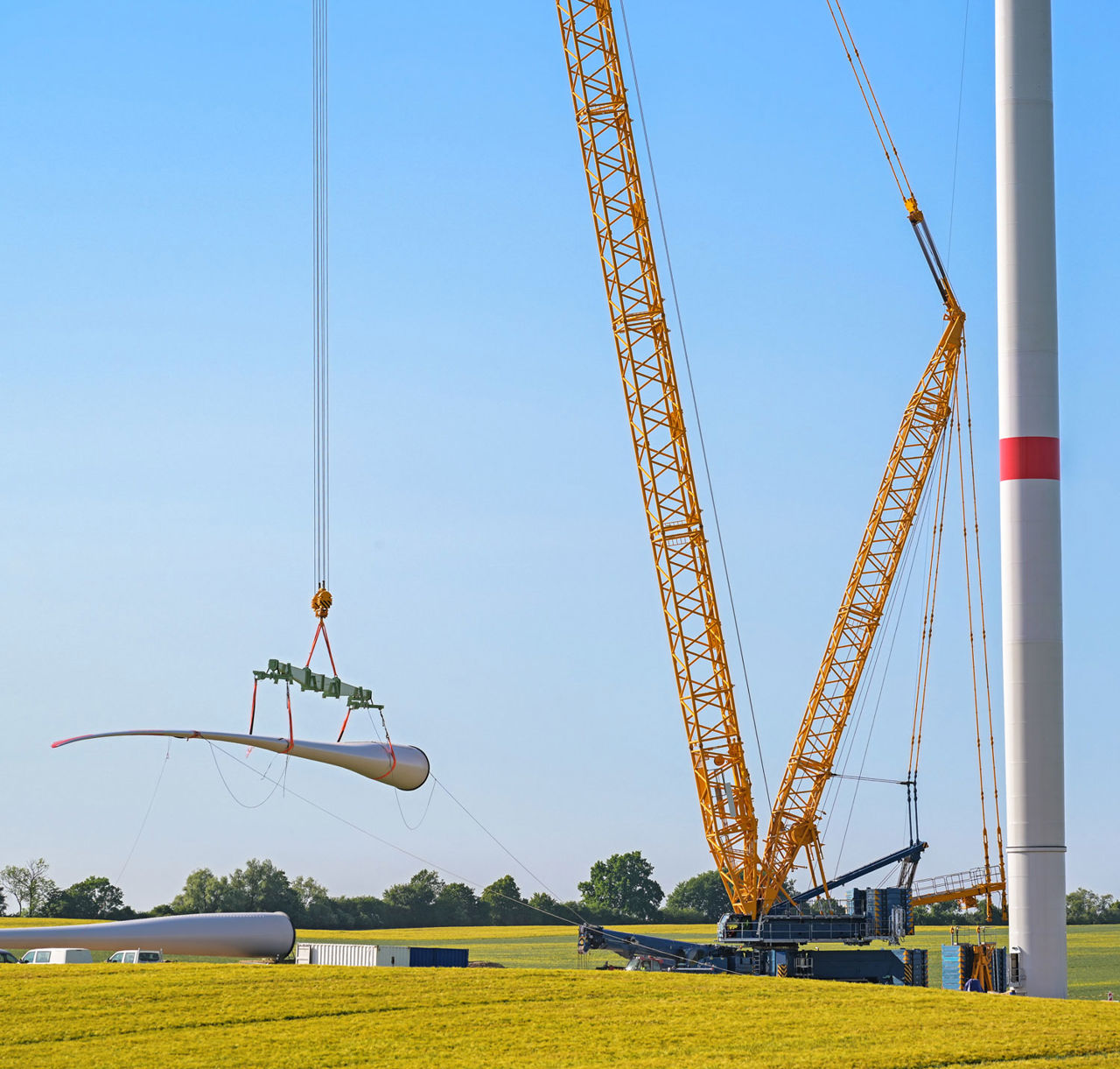 Das Rotorblatt einer Windturbine wird mit einem Kran hochgezogen.