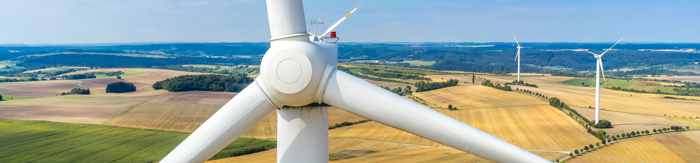 Nahaufnahme einer Winturbine, im Hintergrund ein Feld